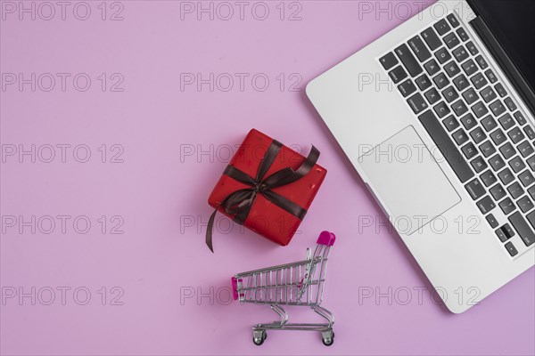 Toy shopping trolley present near laptop keyboard