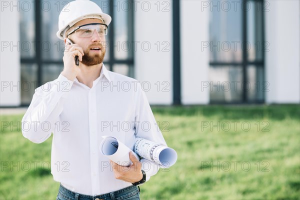 Man with blueprints talking phone