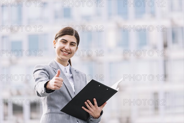 Modern businesswoman with clipboard outdoors