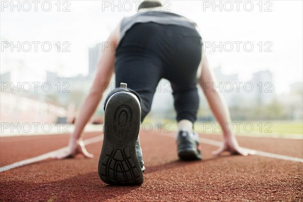 Rear view male athlete taking position red race track
