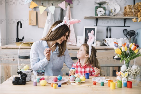 Cute little girl painting eggs easter with mother