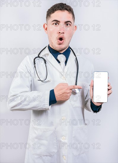 Shocked doctor pointing an application on the cell phone. Amazed young doctor holding and pointing cell phone screen