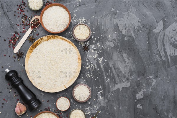 White raw rice with dry spices garlic clove pepper mill concrete backdrop