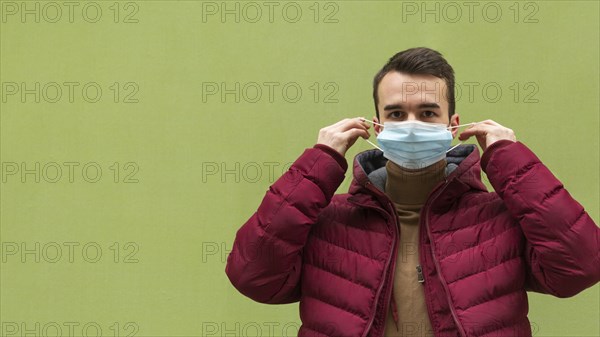 Front view man putting medical mask with copy space