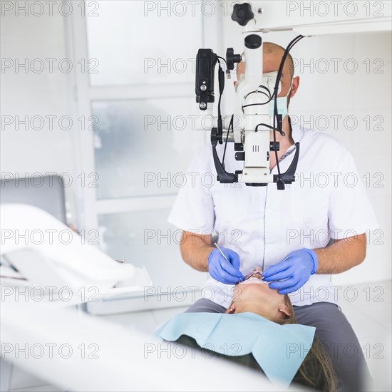Professional dentist examining patient with dental microscope