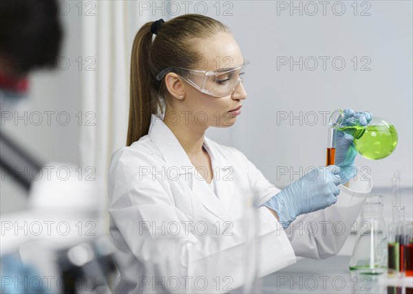 Side view female researcher laboratory with test tubes safety glasses