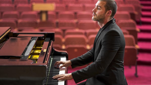 Side view man playing classical piano recital