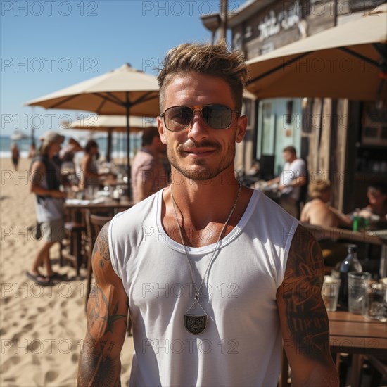 Man with tattoos on upper body on the beach and beach club