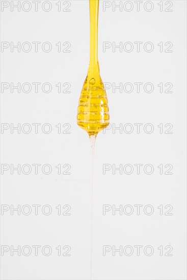 Close up honey dripping from dipper white background