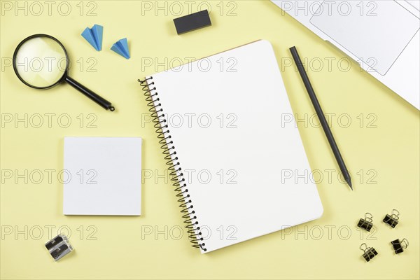 Overhead view office supplies with laptop yellow background