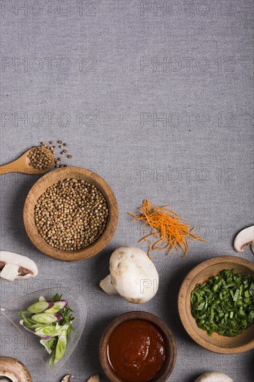 Wooden bowl spring onion coriander seeds sauce mushroom grated carrot grey linen tablecloth