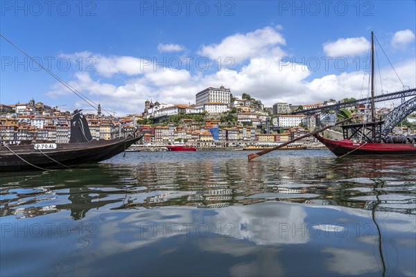 View over the traditional Rabelo boats on the Douro riverbank in Vila Nova de Gaia towards the old town of Porto and the bridge Ponte Dom Luis I