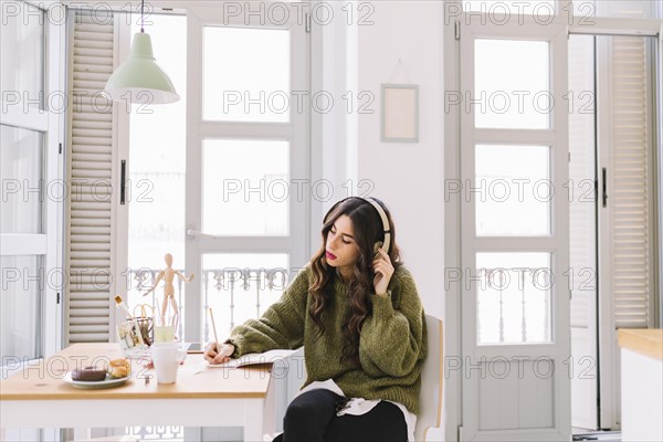 Focused woman drawing listening music