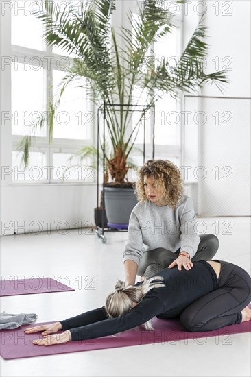 Full shot woman stretching with teacher