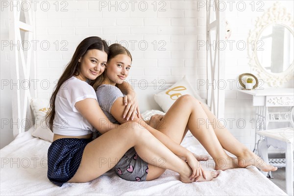 Smiley women hugging bed