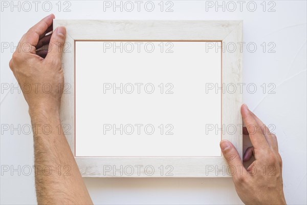Man s hand placing white picture frame wall