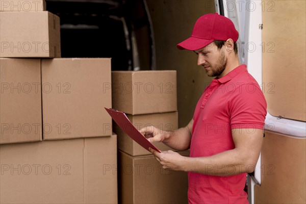 Side view delivery man checking packages list