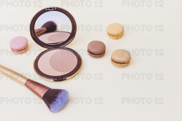Blusher with macaroon makeup brush beige background