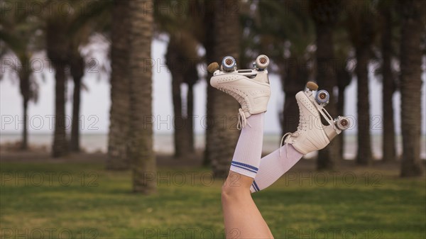 Side view female s leg wearing white roller skate against tree