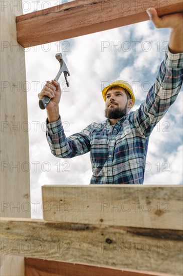 Construction worker with hammer hard hat building roof house