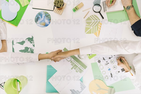 High angle view two businesspeople shaking hands desk