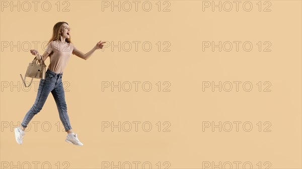 Young female model with hand bag jumping
