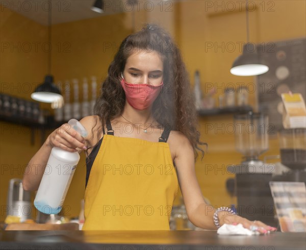 Barista wearing medical mask while cleaning coffee shop