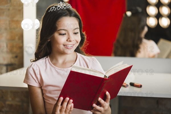 Smiling girl sitting makeup room reading book