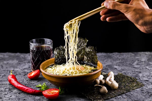 Hand with chopsticks noodles soup