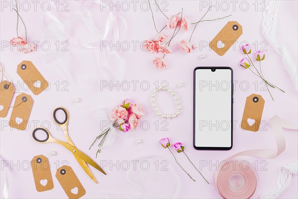 White screen display mobile phone with ribbons roses tags pearl pink backdrop