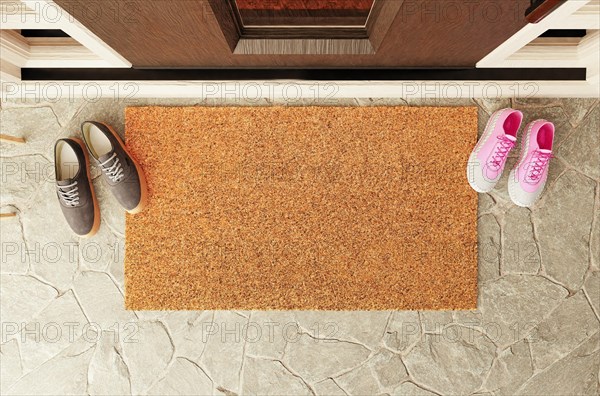 Overhead of blank doormat with man and woman shoes on the porch at the front door