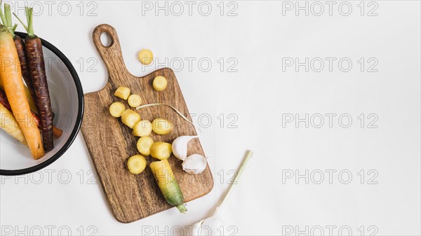 Slices carrot garlic cloves chopping board white background