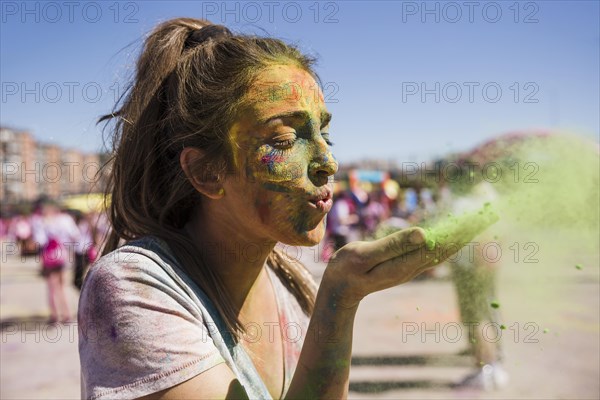 Close up young woman blowing holi color