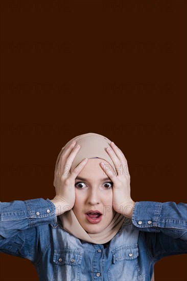 Shocked woman holding her head dark surface