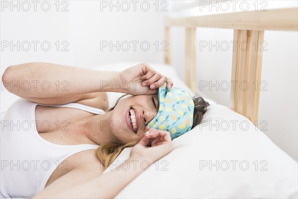 Smiling young woman sleeping bed with eye mask