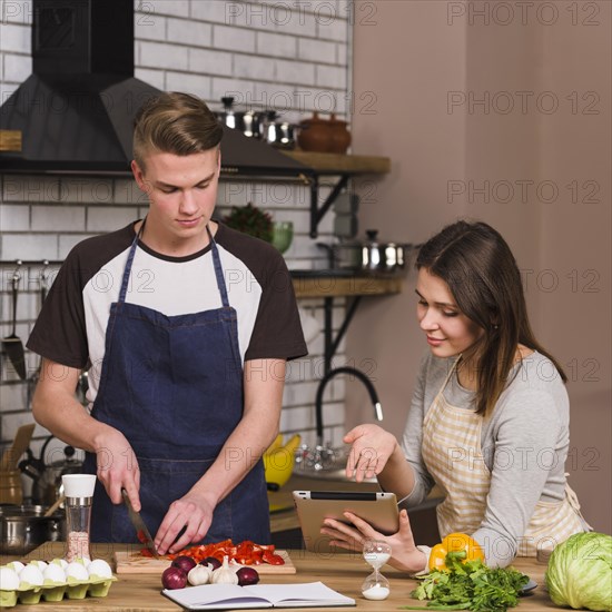 Sweethearts cooking food using tablet