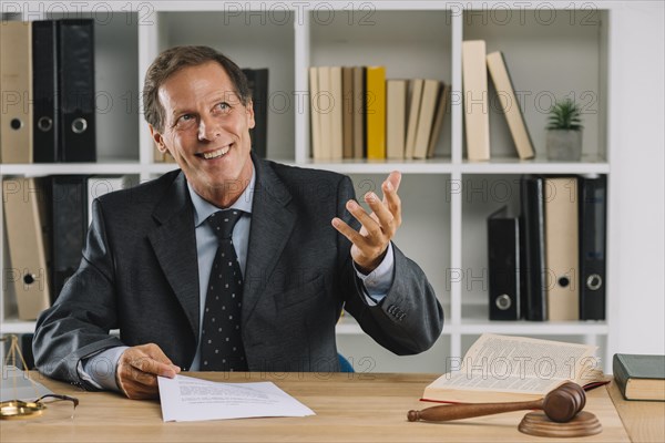 Happy mature lawyer sitting court room gesturing