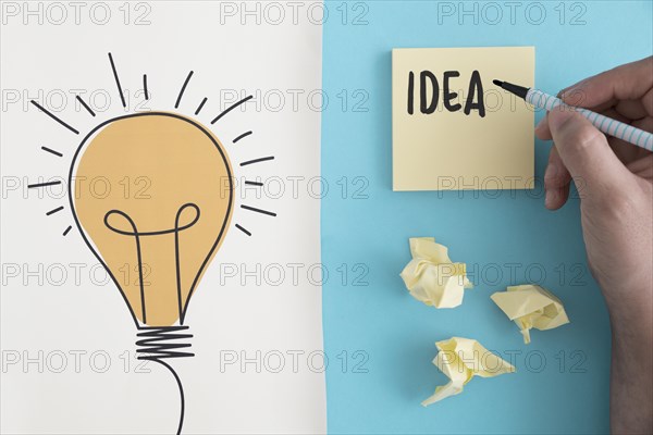 Idea text written with felt pen crumpled ball paper with hand drawn light bulb