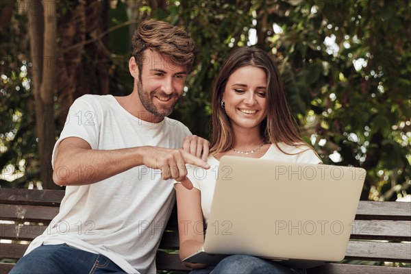 Friends sitting bench with laptop