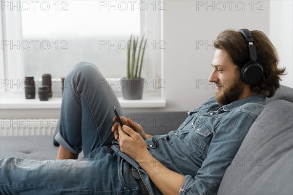 Medium shot man with headphones couch