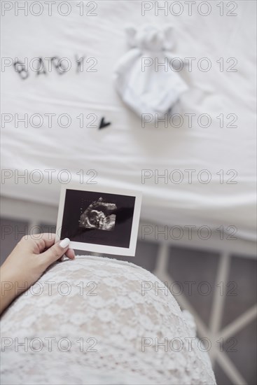 Mother holding x ray fetus close her belly