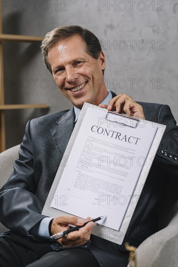 Happy mature lawyer pointing signature place contract document with pen