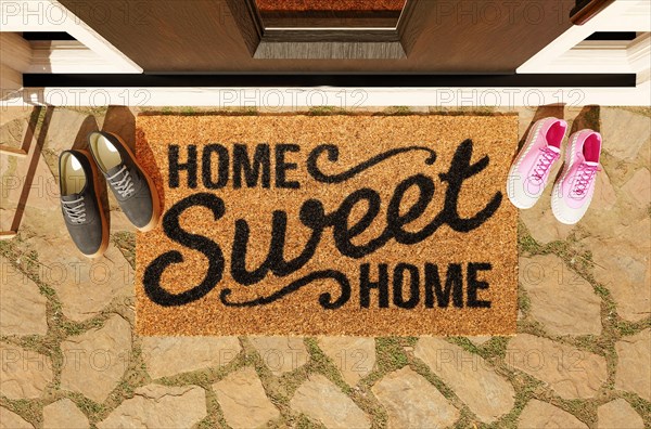 Home sweet home doormat with man and woman shoes on the porch at the front door