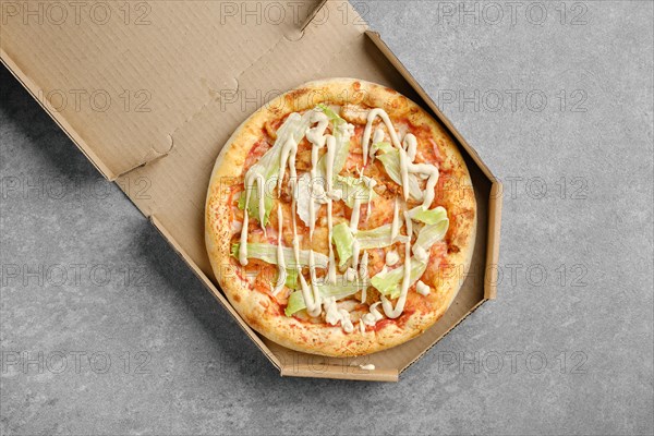 Top view of vegetarian pizza with iceberg lettuce and tomato slices in cardboard box