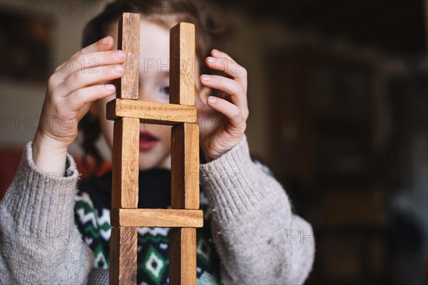 Close up girl balancing stacked wooden blocks