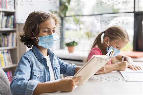 Kids doing their homework while wearing face mask