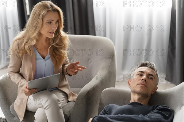 Woman therapist talking man laying couch