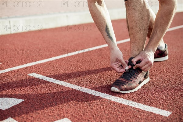 Low section male athlete start line tying his shoelace running track