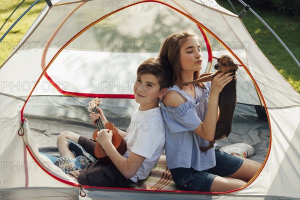 Portrait boy girl sitting tent with holding dog ukulele