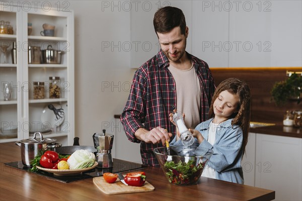 Front view father with daughter preparing food kitchen